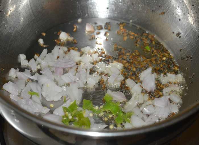 Step two: Heat oil in a deep-bottomed pan. Throw in mustard seeds and cumin seeds. Let them crackle. Add chopped onions and green chilies.
