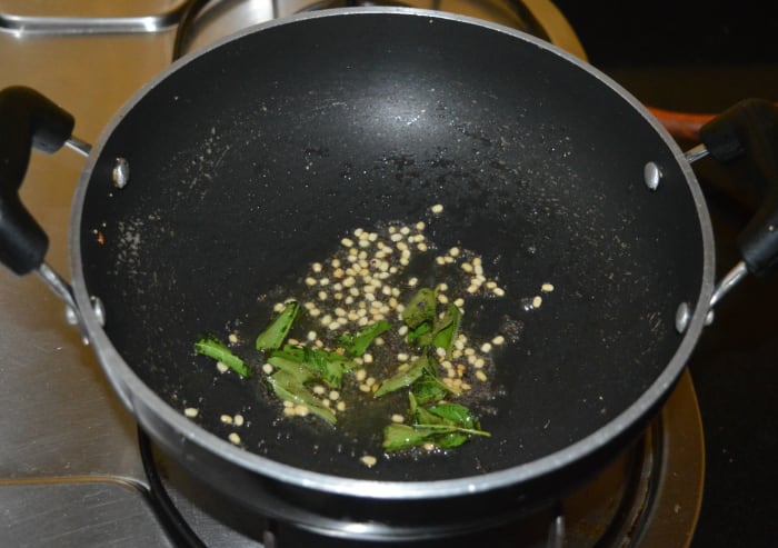 Step two: In the same pan, add some oil or oil and ghee mixture. Keep the heat at medium. Throw in mustard seeds and let them crackle. Add white lentils and curry leaves. Saute until the white lentils become golden brown.
