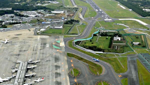 Narita Airport. Note the aeroplanes parked at the terminal on the lower left, the runway at the top, and of course the farmland in the middle of the airport