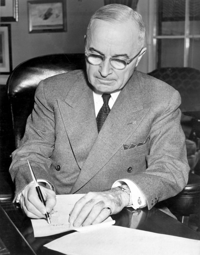 President Harry S. Truman is shown at his desk at the White House signing a proclamation declaring a national emergency.