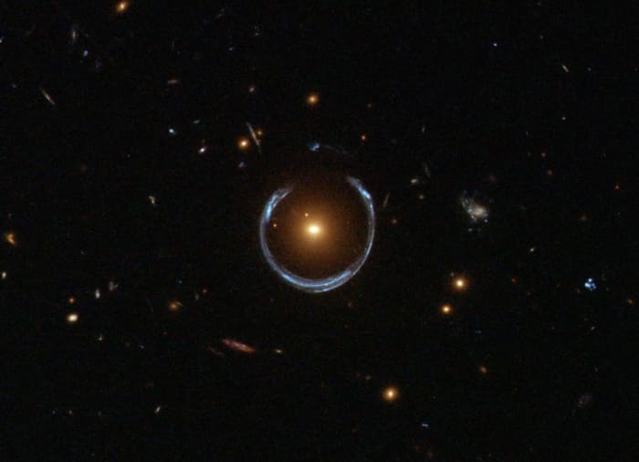 An image from the Hubble Space Telescope showing the characteristic 'Einstein ring' pattern produced by gravitational lensing. The red galaxy acts as a lens for light from a distant blue galaxy. A distant exoplanet would produce a similar effect.