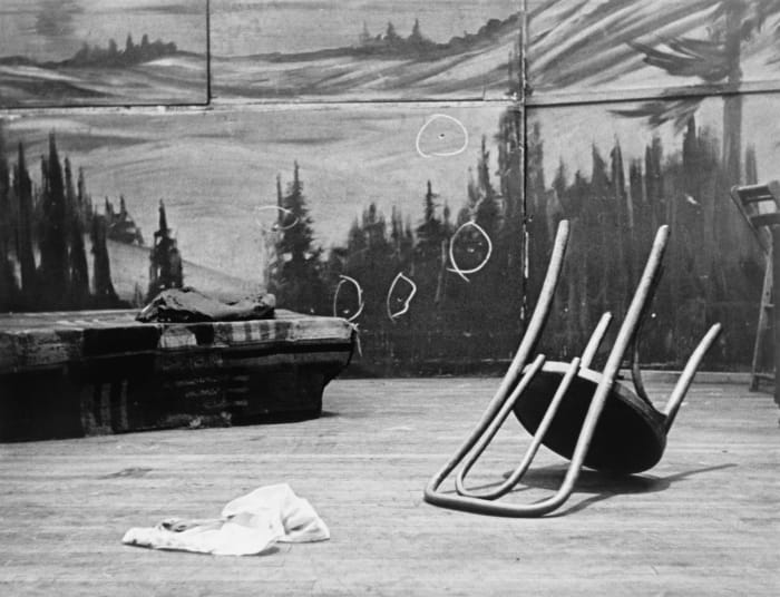 The Audubon Ballroom stage after the assassination. The circles on the backdrop mark bullet holes. During a crowd disturbance, a man with a sawed-off shotgun opened fire, followed by two men with semi-automatic weapons.