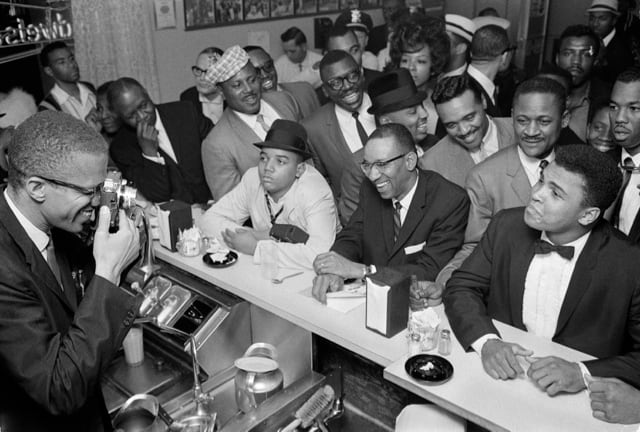 Malcolm X photographing Cassius Clay after Clay became the world heavyweight champion (1964). Clay would become one of the most famous converts to the Nation of Islam, changing his name to Muhammad Ali.