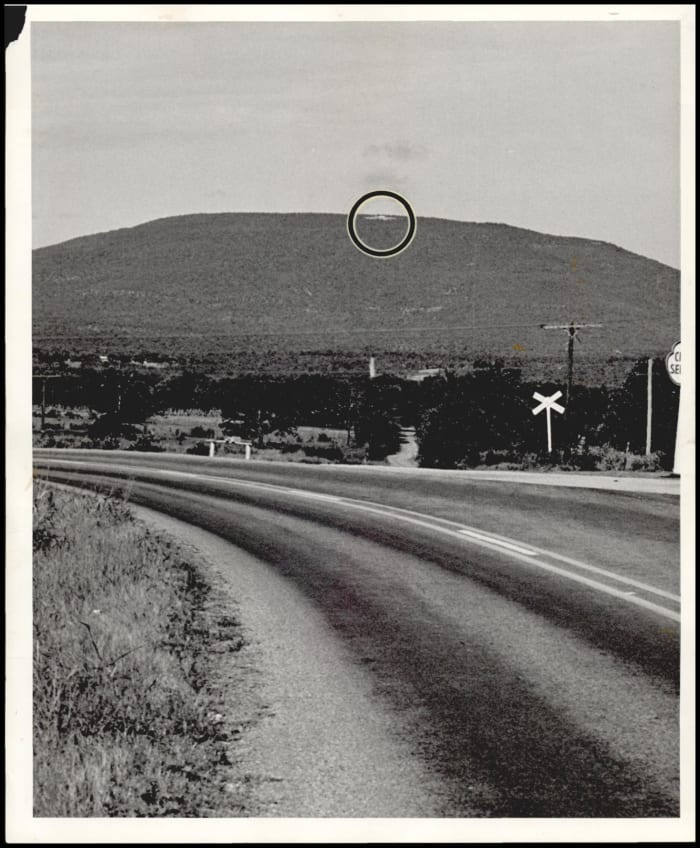 Seen for miles around the area of Poteau where President Kennedy is a visitor this weekend is this tiny speak on top of Mount Cavanal. Photo taken in 1963.