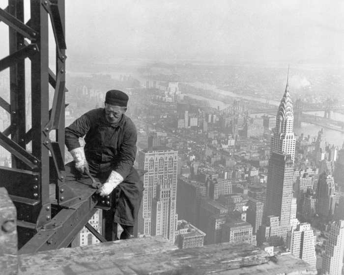 A worker sat on the edge of the Empire State Building with the completed Chrysler Building in the background