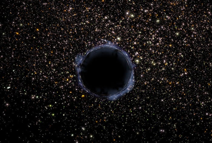 A NASA image of a black hole in the universe. A black hole is an area of infinite density which draws matter and energy into itself