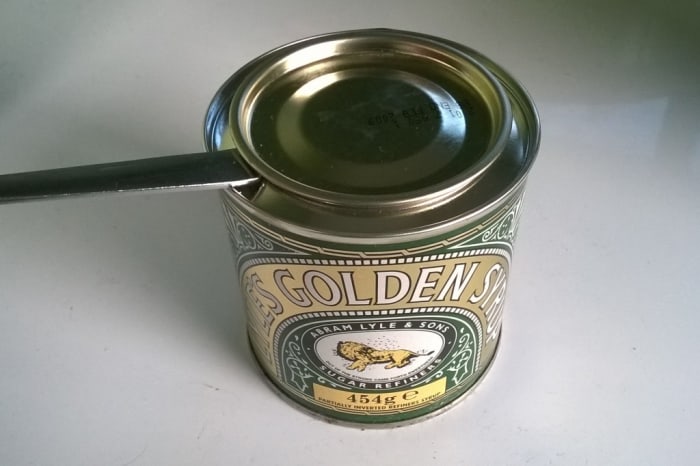 Using the handle of a spoon to open a tin. The spoon acts as a lever, creating a larger force to lift the lid. The fulcrum is the rim of the tin