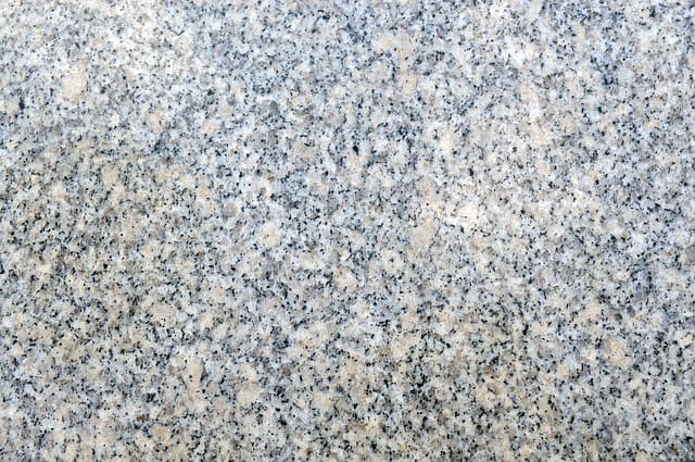 A photograph showing the mineral composition of a slab of granite. The white areas are quartz, the buff-colored parts are feldspar, and the black specs are mica.