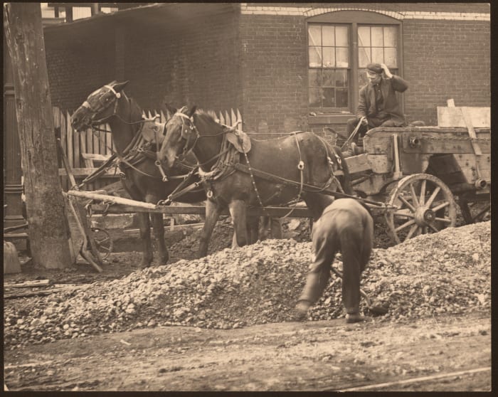 Horse drawn wagon at an unknown street construction site.