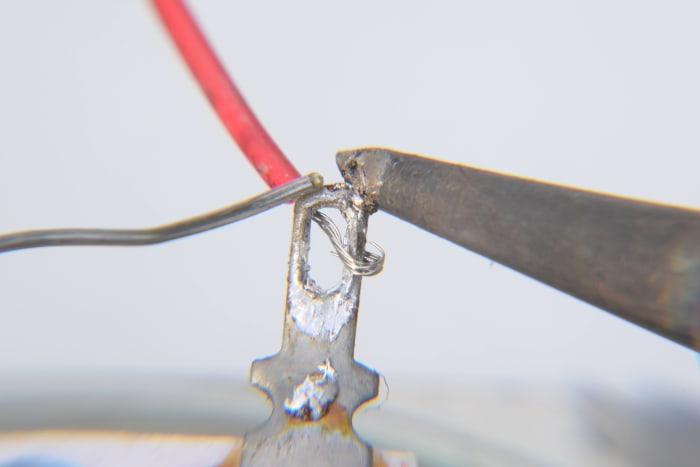 Tin the iron tip and hold it against the tag. After a couple of seconds the tag will be hot enough to melt the solder. Touch the solder wire off the tag, not the iron.