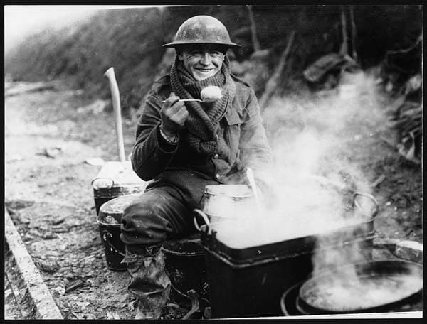 No wonder he looks happy as a soldier enjoys a rare hot meal, probably a potato.