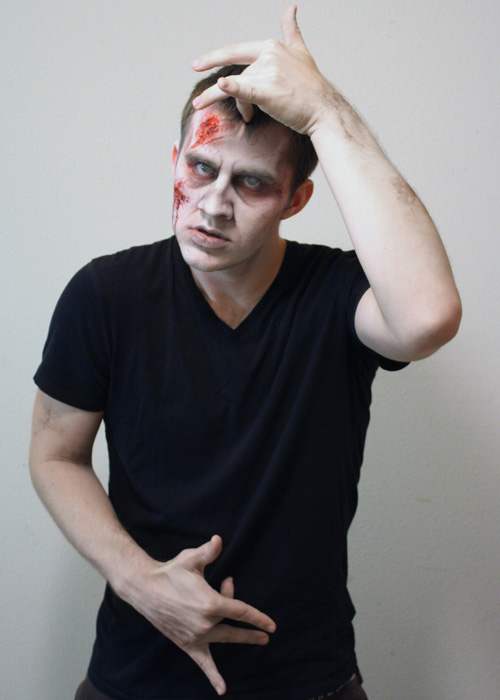 The middle finger of the right hand is held to the abdomen and the middle finger of left hand is held to the forehead.