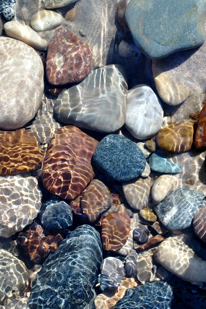 Brown Stones, Basalt and more in Pier Cove Creek exposed during snow melt exposed by rushing water flow.