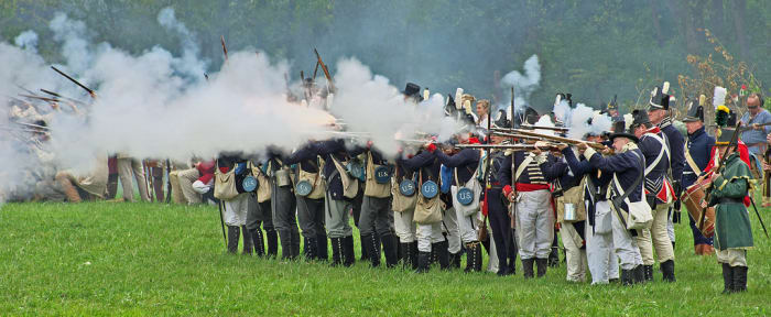 Volley of flintlock musketry from American regular infantry and militia.