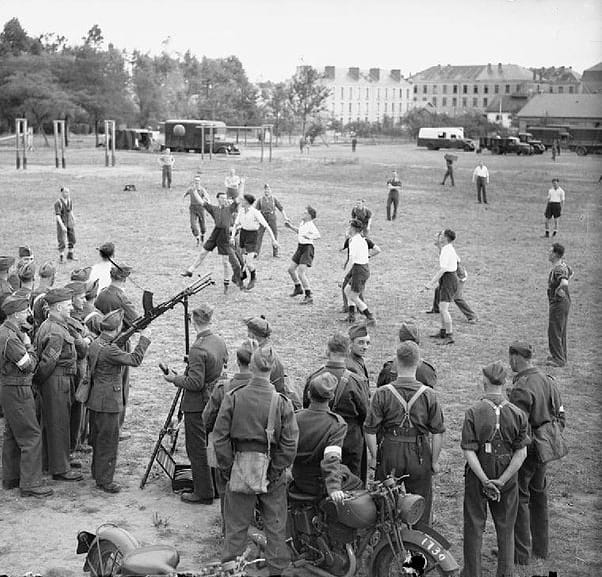 British soldiers playing football (soccer) in Le Mans, France during the Phoney War (1939-40). Note the gun mounted on a tripod in case the Germans attacked from the air.