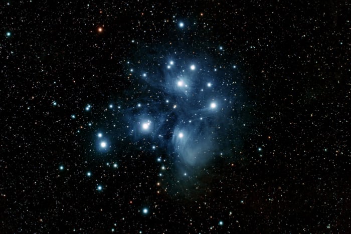 The Pleiades Star Cluster (described above). Sadly this degree of resolution will not be possible in binoculars, but the cluster remains one of the best binocular sights in the sky. The blue haze is a reflection nebula (described below)