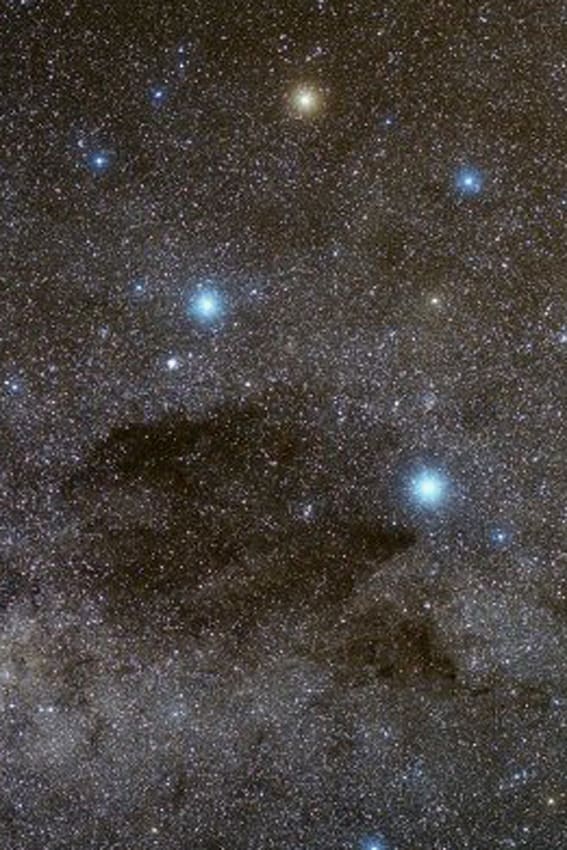 The Coalsack Dark Nebula visible against the bright glow of the Milky Way. The four brightest stars are the primary stars of the Southern Cross Constellation
