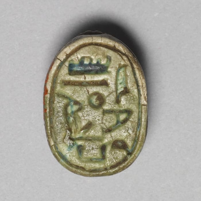 This scarab has the name of Pharaoh Hatshepsut, along with an epithet that discusses her relationship with the god Amun. Due to Amun being a god, his name is written much larger than the female pharaoh's.