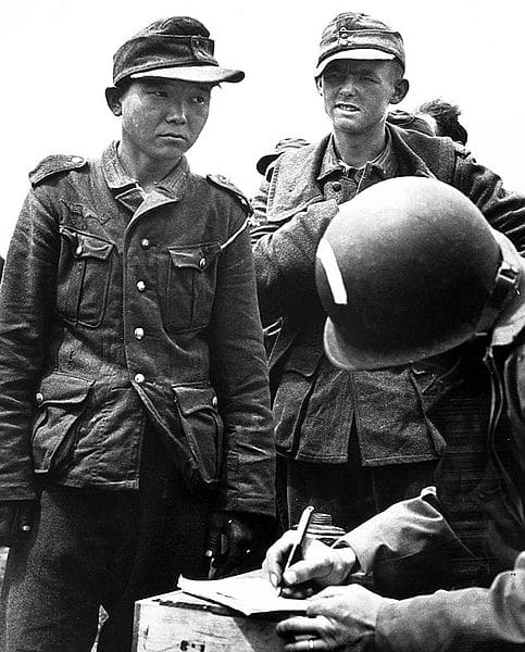 WWII: Yang Kyoungjong, an ethnic Korean soldier in the German Wehrmacht, captured by US Army soldiers in France after D-Day in June 1944. Date June 1944