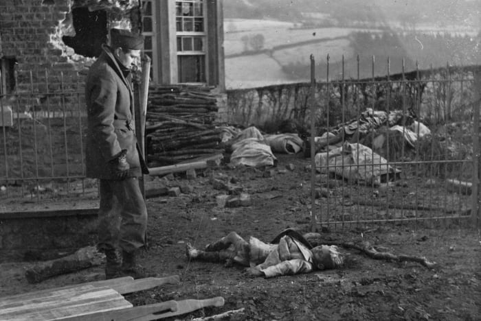 A war correspondent stares in disbelief at the body of a little girl killed by the Germans in Stavelot, Belgium. She was one of a 111 civilians massacred by the Nazis.