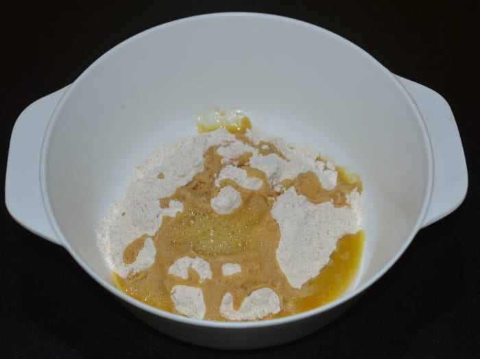 In a large mixing bowl, add wheat flour, and a little bit salt. Add the hot ghee. You will hear a sizzling sound. Mix it with a spoon. Once the heat reduces, continue to mix with your fingers.