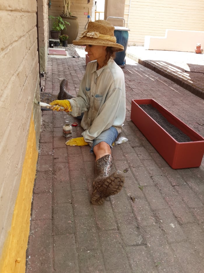 Charmaine, age 62, painting the wall. Every opportunity is used to get some exercise - in this case doing the splits! Sedgefield, South Africa.