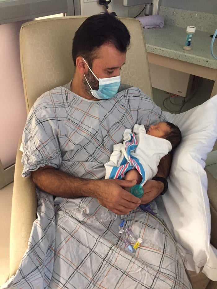 This is a picture of my dad visiting our little guy in the NICU. The NICU had specific rules for visitors and we only allowed our parents to visit the baby while he was in there. **Notice the face mask and scrubs- they were mandatory during visits.