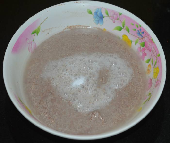 Step three: Prepare the steamer or cooker. Grease the idli moulds with ghee or oil. Add Eno fruit salt or cooking soda to the batter and gently mix.