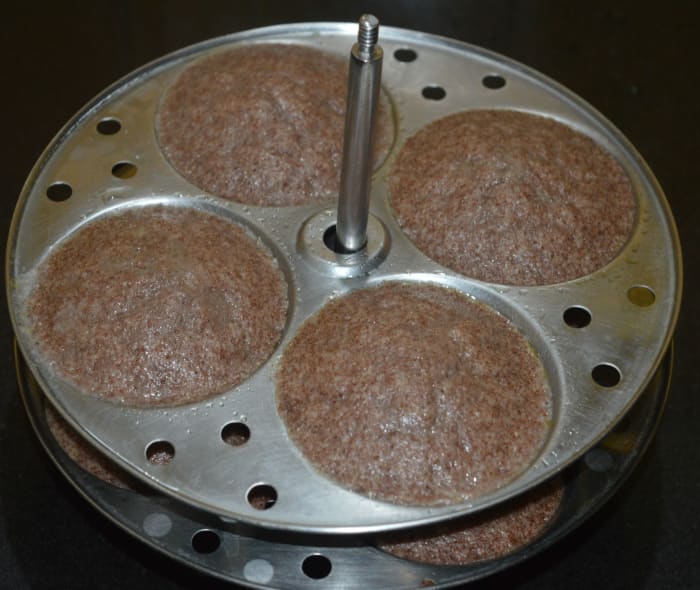 Open the steamer lid and take out the idli stand. Allow it to cool for 5-6 minutes. Next, run a spoon handle or knife around the mould to take out the idlis from the mould. Store them in a closed container.