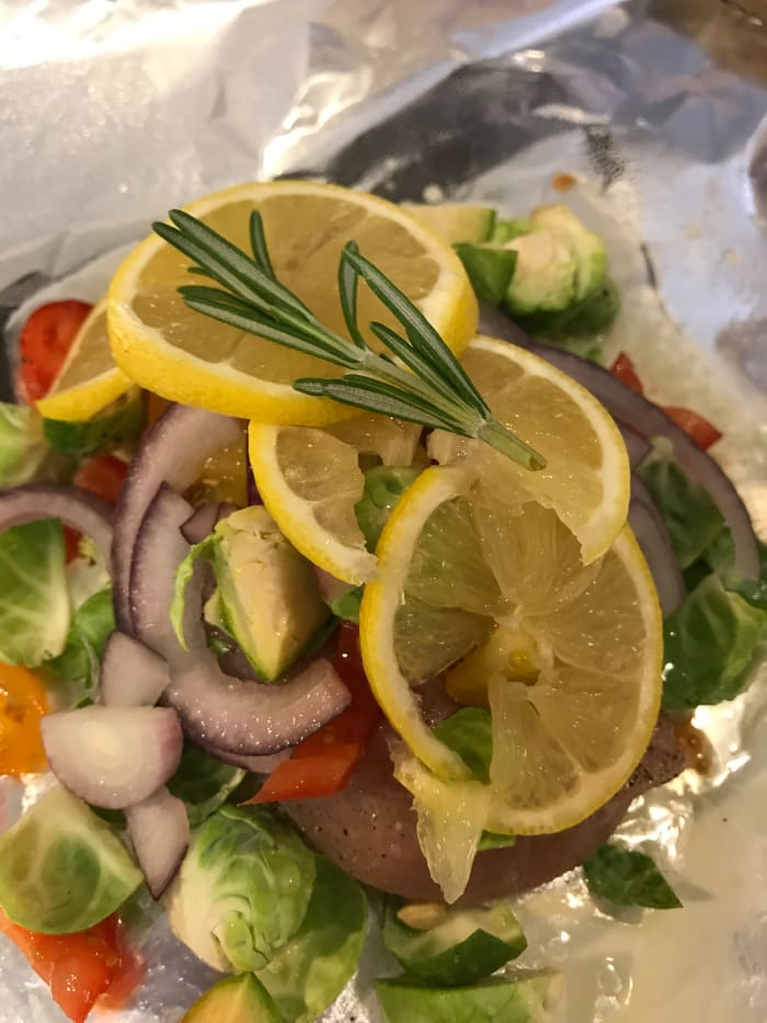 Squeeze the juice from half a lemon over the ingredients. Slice the other half into thin slices, and layer them over the top of the other ingredients. Place a small sprig of fresh rosemary on top of the entire thing. Classic flavor!