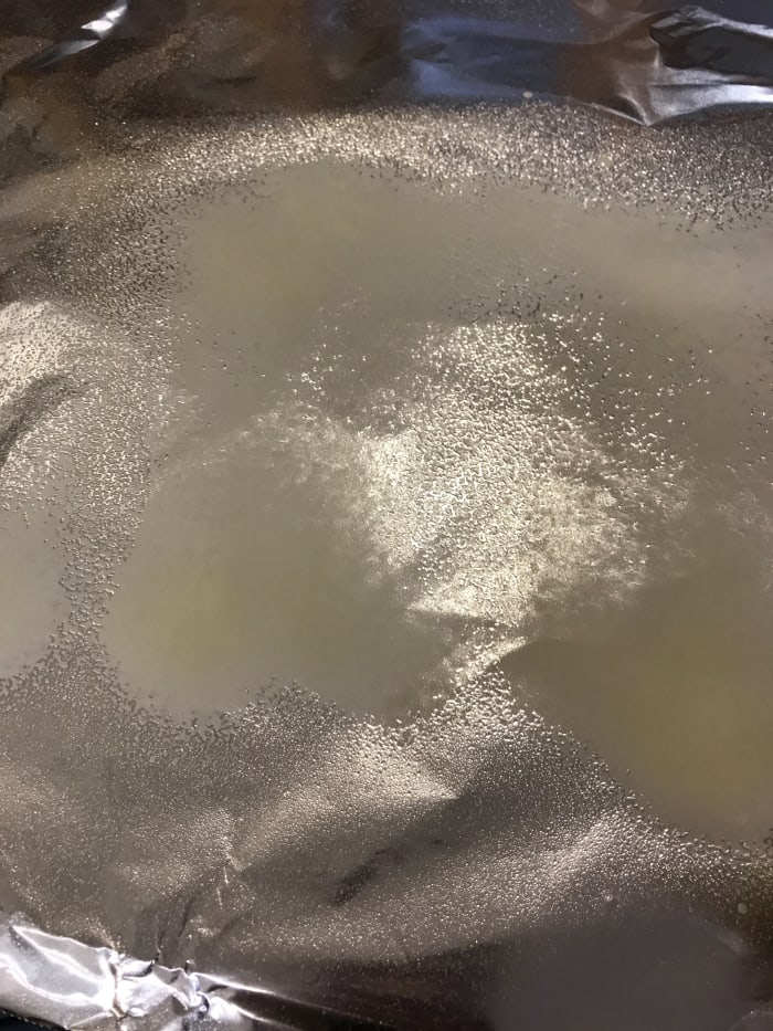 Use just a little bit of butter on the parchment or foil, or in this case, plain cooking spray. The food steams in the packet, so this is simply to prevent the chicken from sticking to the foil or parchment.