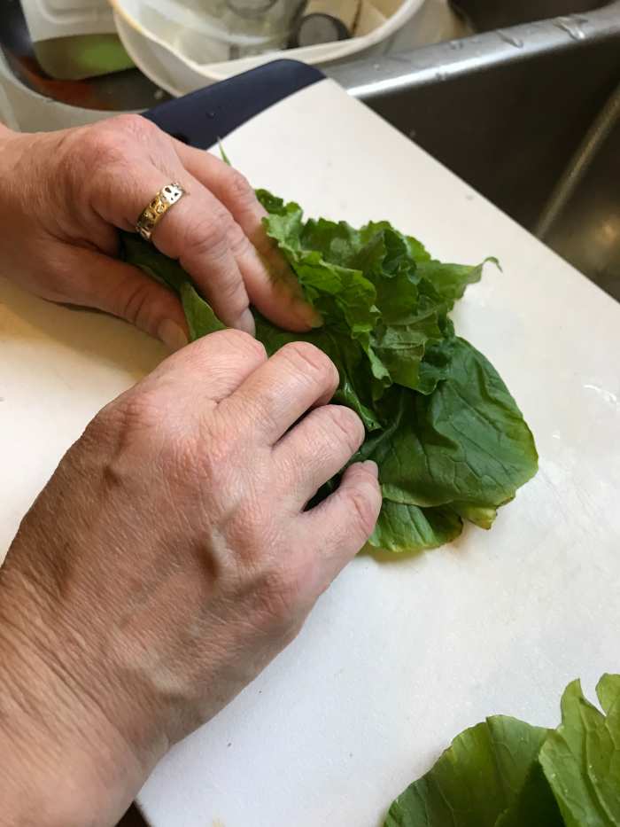 Place 5-6 leaves on top of each other and roll them tightly into a bunch. You can skip this step, but it makes the finished dish much easier to cut and eat.