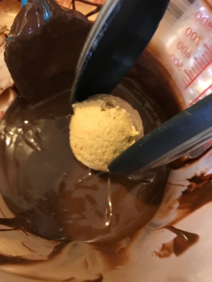 Dip the chilled peanut butter balls into the melted chocolate about halfway, or maybe a bit more. You want to leave a good portion of the candy exposed, to get the classic dark and light brown look.