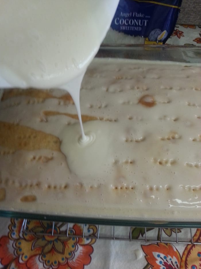 After mixing the real cream of coconut milk with the sweetened, condensed milk, it is time to pour it over the warm cake with holes poked into it.