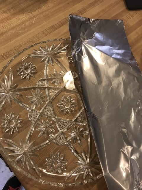 Prepare a cake plate by placing strips of foil along the edges, making sure to leave the center of the plate uncovered. Place a dollop of frosting in the center of the plate.