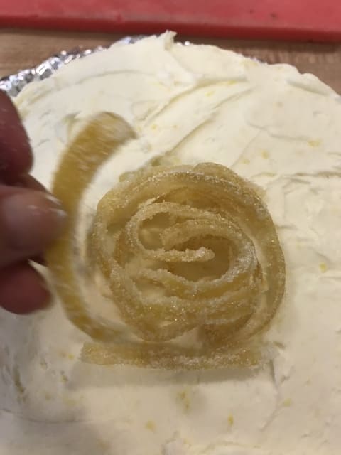 Once the crumb coat has chilled, frost the entire cake with the remaining lemon buttercream. Garnish with candied lemon peel for a beautiful presentation!