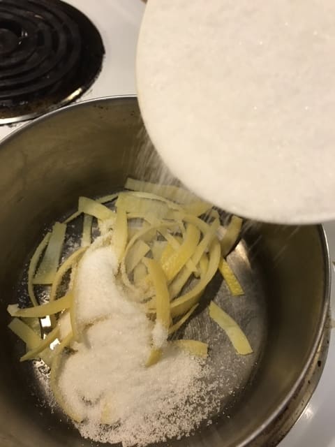 After the lemon peel is drained the third time, you're ready to begin the candying process. Return the lemon zest to the saucepan. Make a simple syrup of one cup white sugar and one cup cold water.