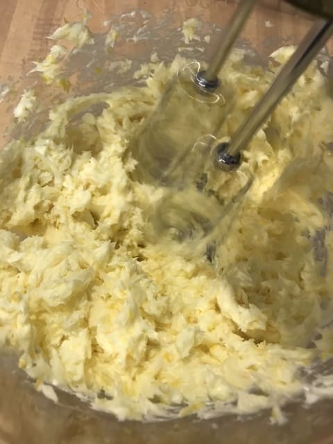The butter and lemon zest are beaten with a mixer until light and fluffy. This gives the finished frosting it's beautiful consistency, so a little patience here works wonders. Keep beating the butter and lemon zest until it lightens in color.