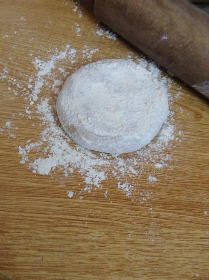 Cover the ball of dough with dry flour while flattening it. This will prevent it from sticking on the wooden board.