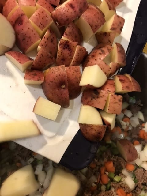Stir in the potatoes once the onions have become fragrant and stir well. You're ready to add the broth!