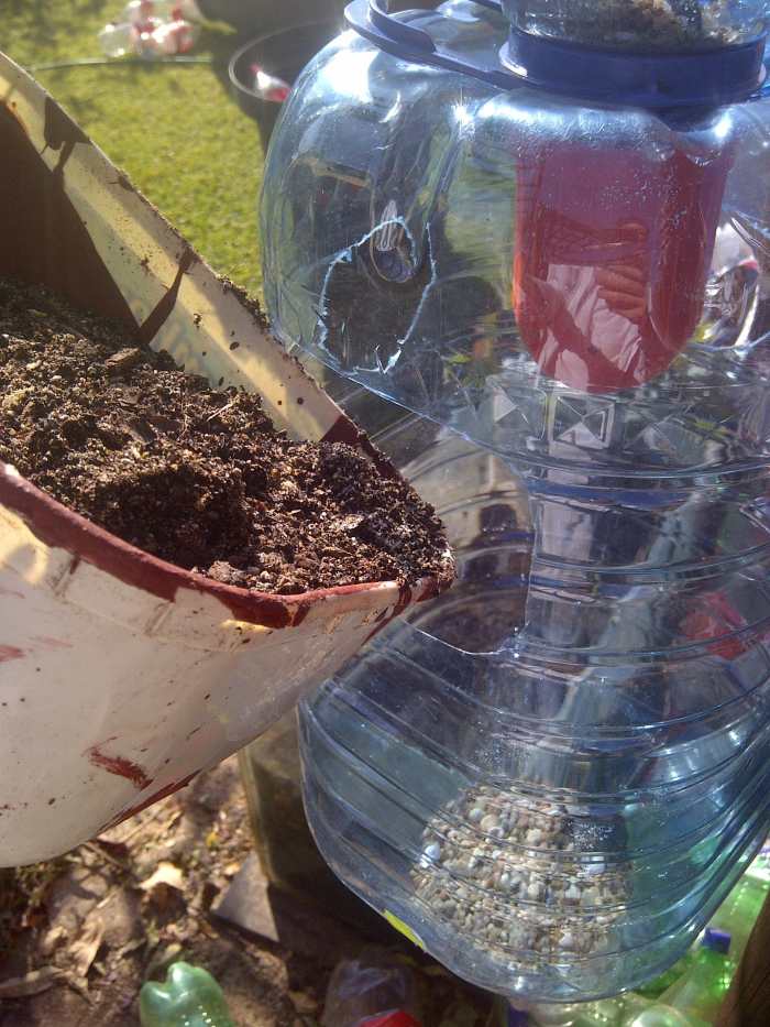 Filling up your containers with potting soil. Can you see the gravel at the bottom? It will help with drainage.