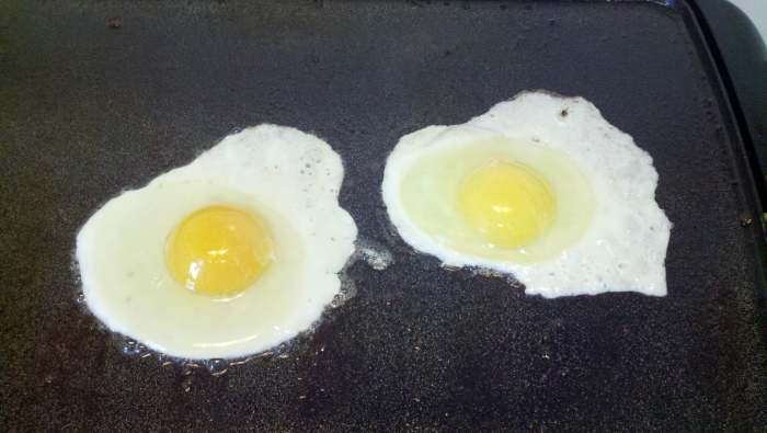 One of our eggs frying on the left next to a store one on the right. See the difference in yolk color?