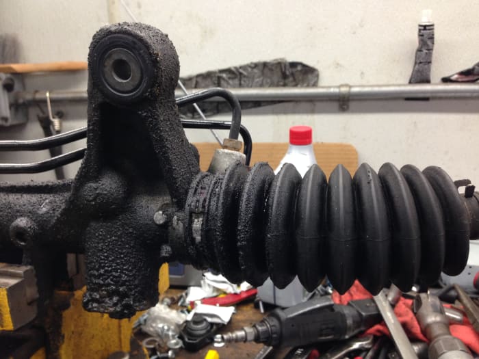 Leaking steering rack end seal. The possible cause is that the rack end bushing has too much play.