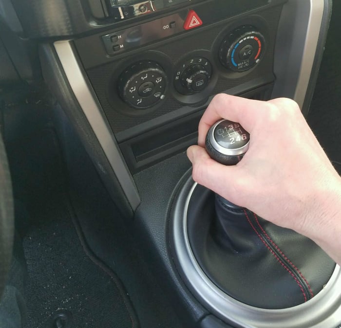 Press the clutch in all the way and move the gear shift into first gear. Usually this is to the left and up away from you.