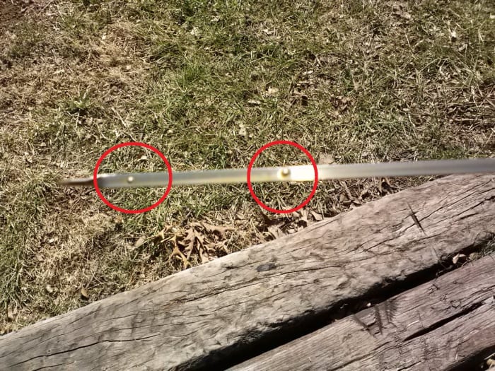 Closeup of the engine oil dipstick, circled dot in left of photo indicates lower mark, circled dot in right of photo indicated the upper or "FULL" mark