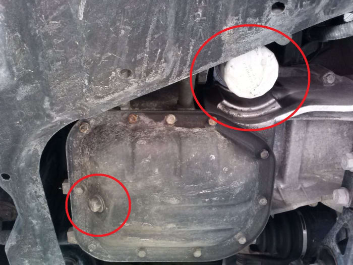 In the lower left, we see the oil drain bolt which requires a 14 mm socket to remove and in the upper right of this photo, we see the oil filter which can generally be removed by hand without any additional tools.