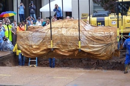 As hundreds of people watch, Miss Belvedere is lifted out of her watery tomb still covered in its "waterproof" plastic cover.