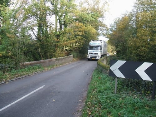 A big lorry on a small bridge in rural England.