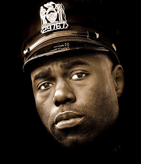 A cop expresses the cumulative effects of his job in his eyes.