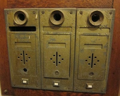These old style apartment mailboxes, complete with speaking tubes, must have been real mailman knuckle-busters.